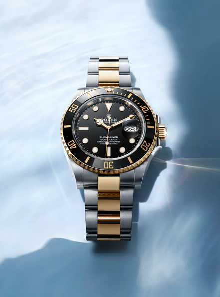 Silver, Black & Gold Rolex Submariner on a blue background
