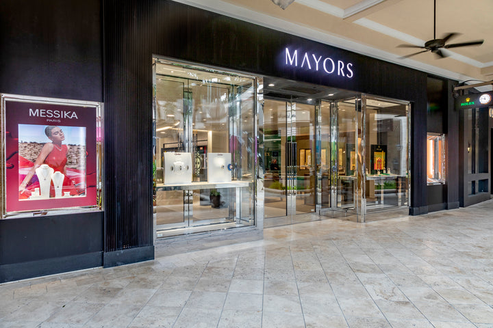 Exterior of MAYORS jewelry store with glass doors and a Messika Paris advertisement on the left.