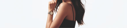 Woman in a black sleeveless top wearing a watch, with long hair, shown from the shoulders up.