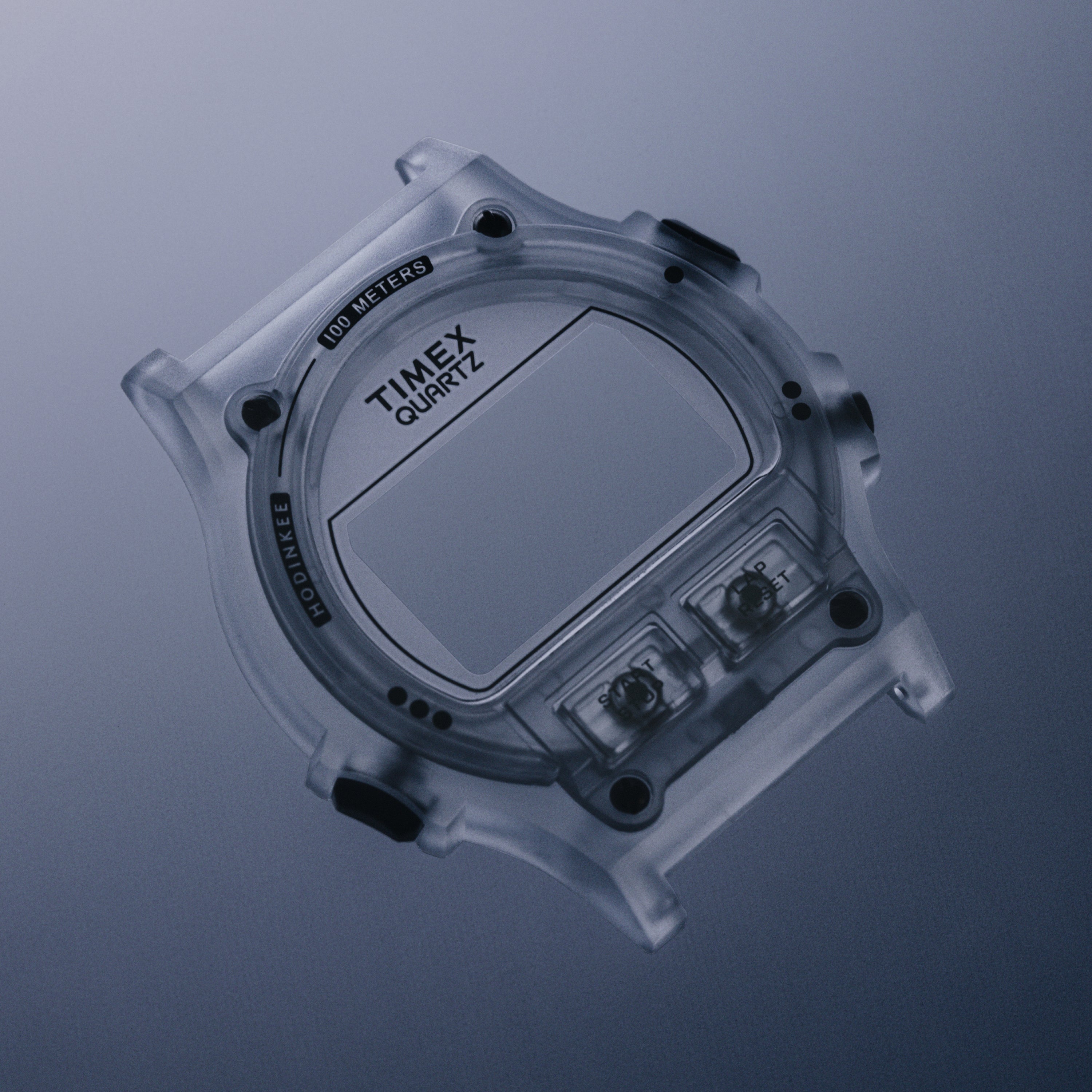 Clear translucent digital watch with square face, "TIMEX QUARTZ" dial, two side buttons, and "100 METERS" marking.