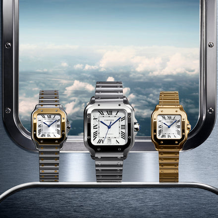 A close view of three Cartier watches in mixed metal, silver toned metal, and gold metal, displayed in front of a window with a view from the sky as if from an airplane