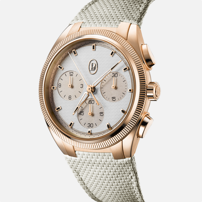 The Parmigiani Fleurier TONDA PF Sport is a gold chronograph wristwatch featuring a white textured dial and beige fabric strap, shown against a white background.
