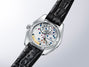 Grand Seiko 44GS watch with silver case, white dial, colorful jeweled movement visible through caseback, and black crocodile 