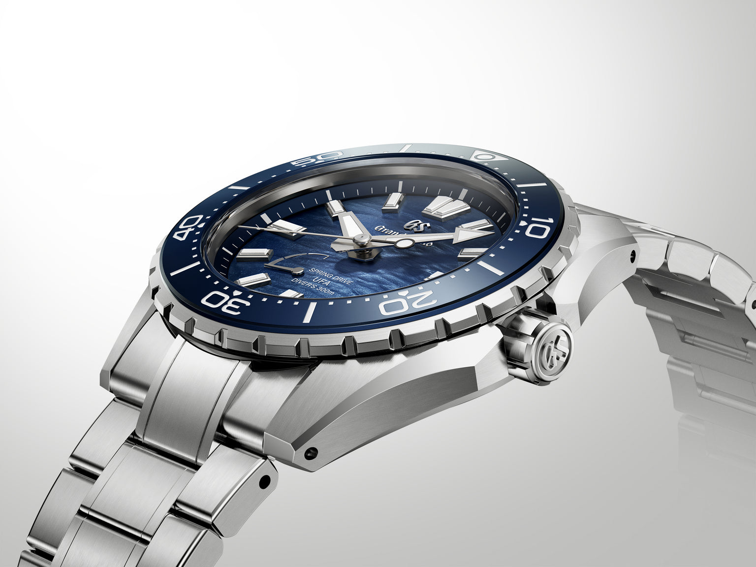 Stainless steel diver watch with dark blue dial, rotating bezel, and matching metal bracelet displayed against neutral backgr