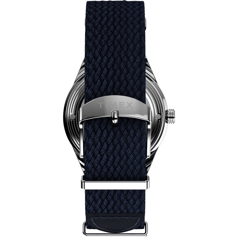 Close-up of the back of the Timex Marlin® Jet Automatic, featuring a navy blue woven strap and a silver TIMEX-engraved buckle. The metallic case reflects the retro-futuristic style iconic to this timepiece.
