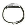 Side view of the Timex G SS MW SW MK1 36 BLK DL GRN STP 25 military-style watch, featuring a silver case and green recycled fabric strap with visible crown, buckle, and loops. The watch face is not shown.
