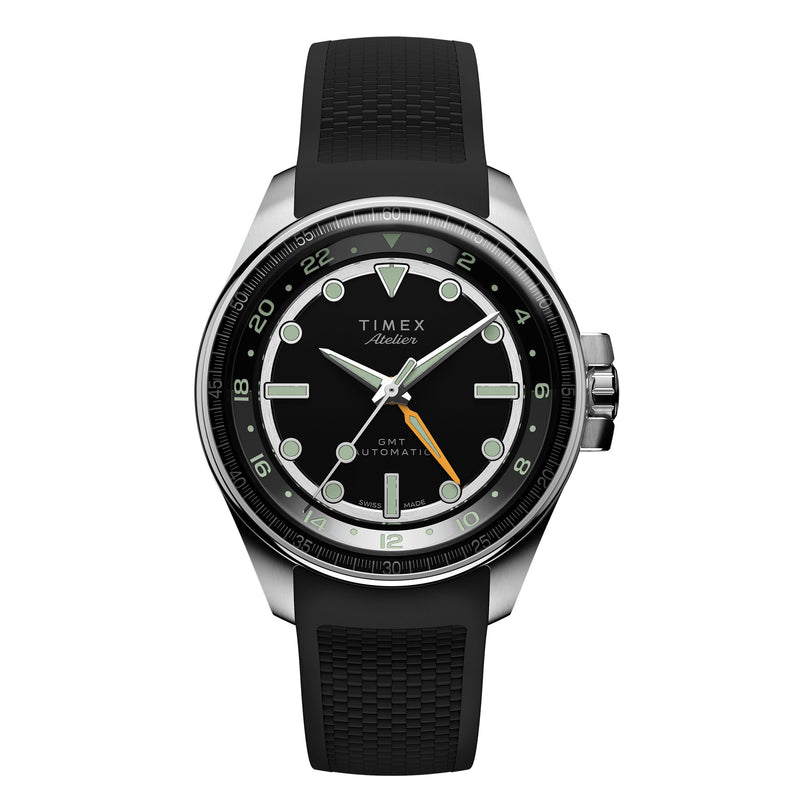 A Timex Atelier GMT24 M1a Swiss Made Automatic wristwatch with a black dial, silver hour markers, black bezel, orange GMT hand, and a black textured rubber strap. The watch face reads Timex Atelier GMT24.