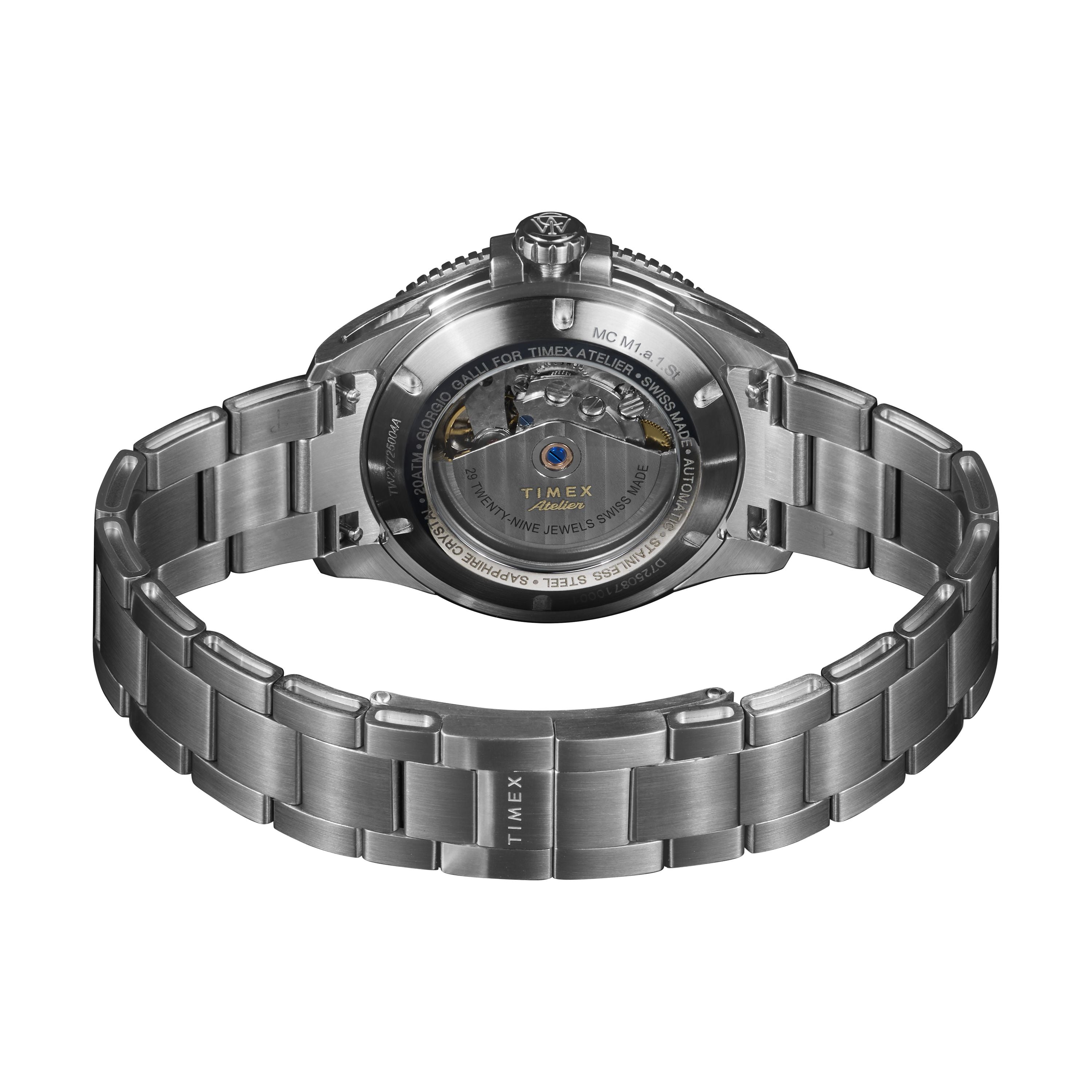 A close-up of the Timex Atelier Marine M1a Swiss Made Automatic highlights its minimalist design, transparent case back revealing the mechanism, and an open metal bracelet with “TIMEX” engraved on the clasp.