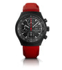 Black chronograph watch with numbered dial, red central hand, day-date window, and red leather strap.