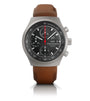 Titanium chronograph watch with black dial, tachymeter bezel, red center hand, date window, and brown leather strap.