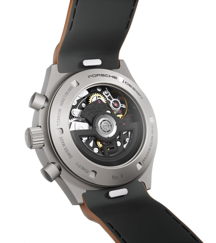 Titanium chronograph watch with visible skeleton movement, black leather strap, and numbered edition marking on case back.
