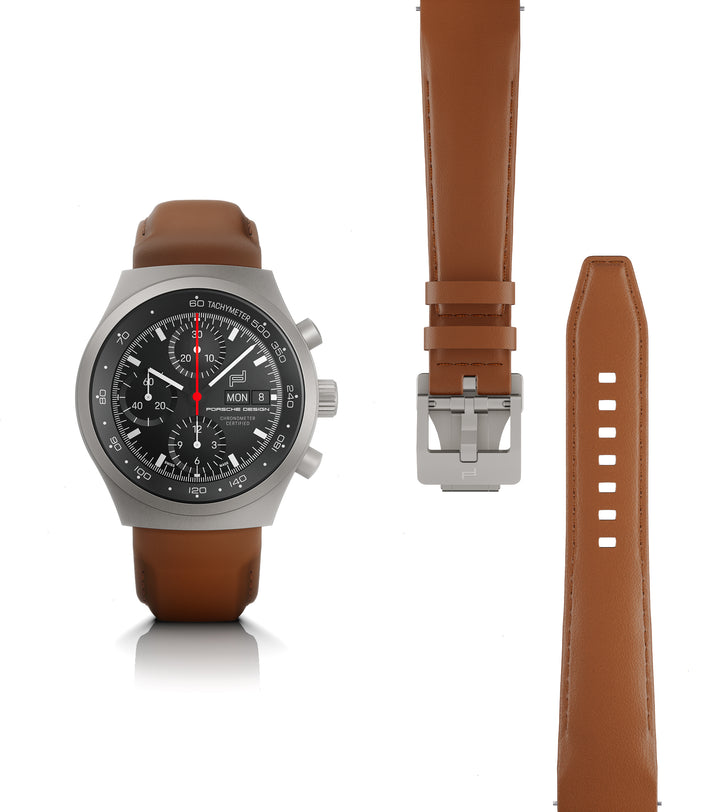 Titanium chronograph watch with black dial, red chronograph hand, and brown leather strap shown with extra strap and buckle.