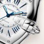 Cartier Roadster watch with white dial, blue hands and markers, date window showing 18, stainless steel case and bracelet.
