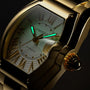 Gold-tone Cartier Roadster watch with rectangular face, cream dial, Roman numerals, and luminous hands against black backgrou