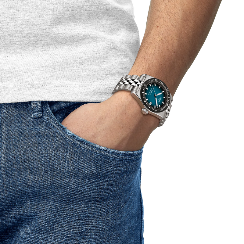 Person wearing a silver watch with a blue face on a white background