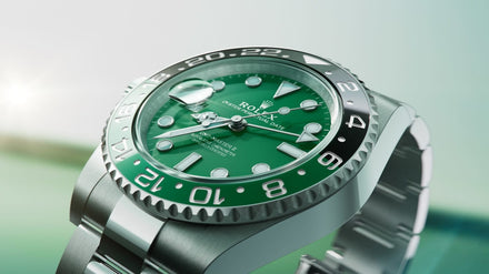 A close-up of a green dial Rolex GMT-Master II watch with a silver and black bezel.