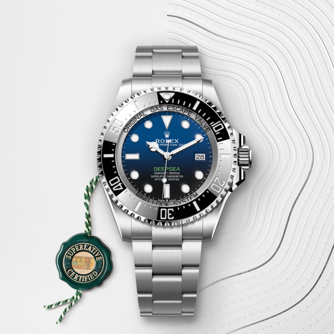 A Rolex Deepsea watch with a blue-black dial and metal band, next to a green Superlative Certified tag.