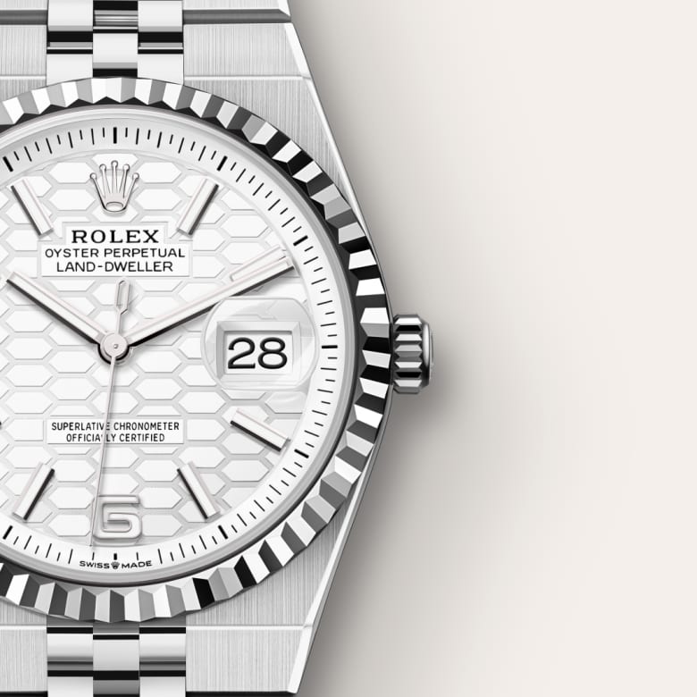 Close-up of a silver Rolex watch with a white hexagonal-patterned face, date display, and metal band.