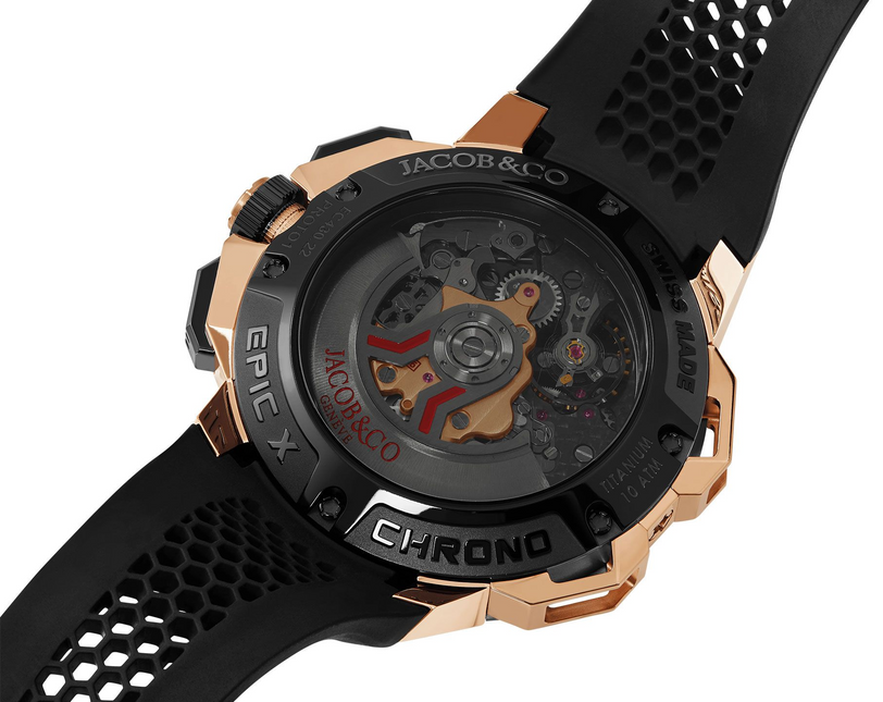 Rose gold and black chronograph watch with visible mechanical movement through transparent case back and perforated rubber st