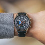 A person wears an OMEGA Speedmaster Hodinkee 10th Anniversary Limited Edition with a black strap and detailed black chronograph dial on their left wrist.