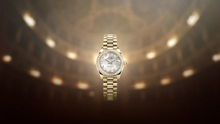 A gold luxury wristwatch with a diamond bezel displayed on a blurred, elegant background.