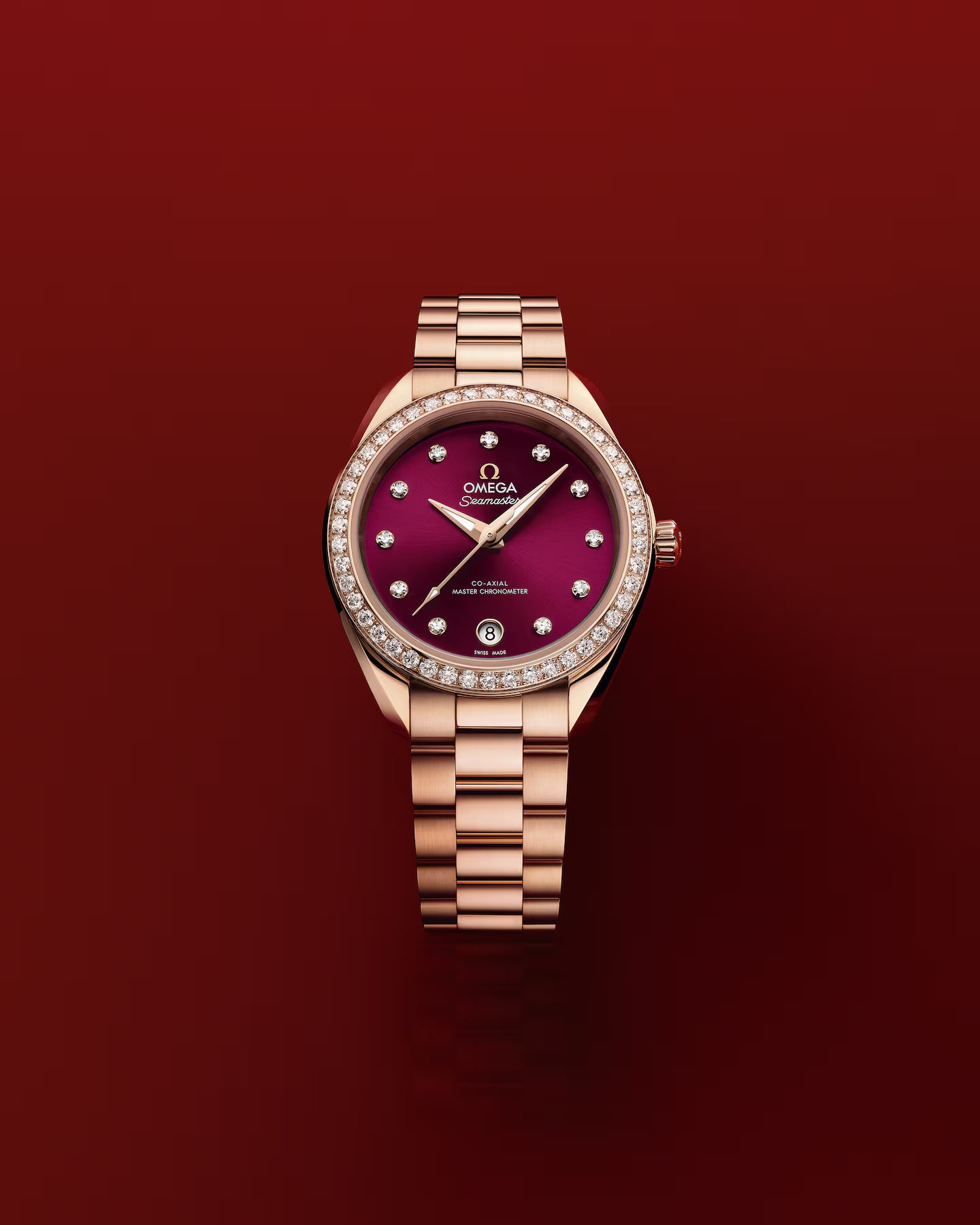 Omega Seamaster watch with a burgundy dial and diamonds at the hour marks with a rose-gold bracelet over a red background