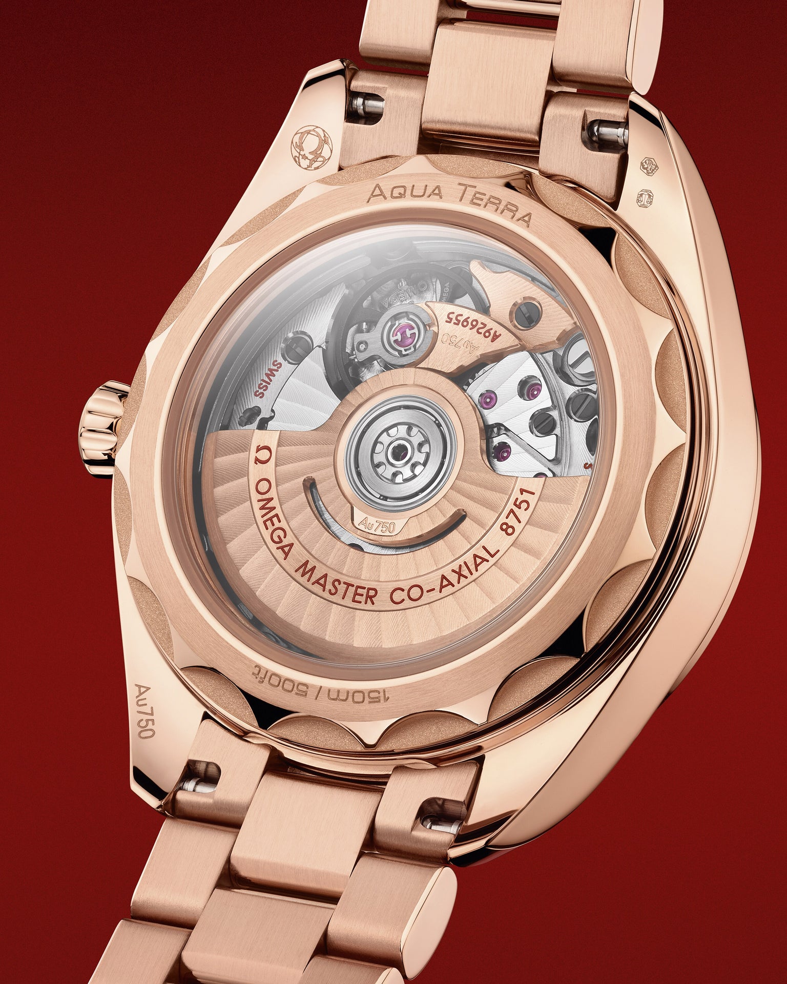 The back of a watch case showing the mechanism and the words Omega Master Co-Axial and Aqua Terra on the rose-gold watch