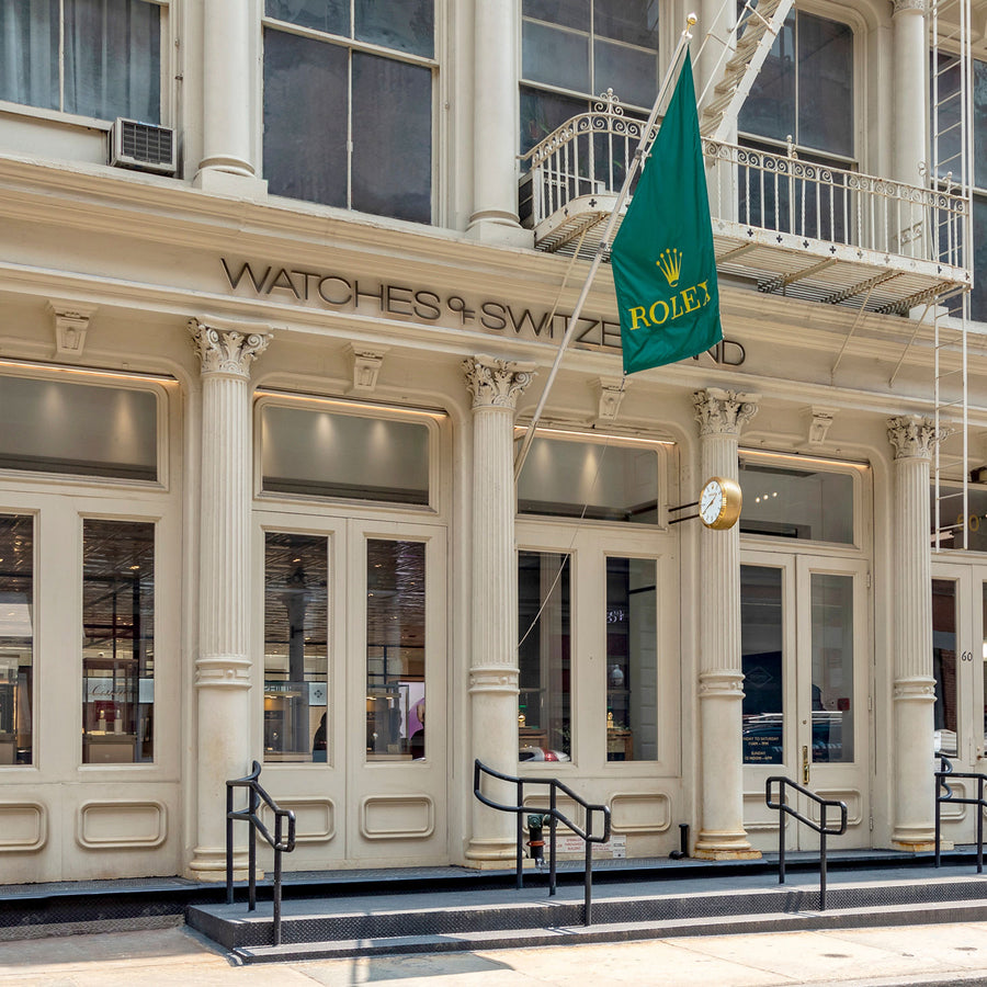 Rolex green flag outside the Watches of Switzerland store with cream columns and large windows.