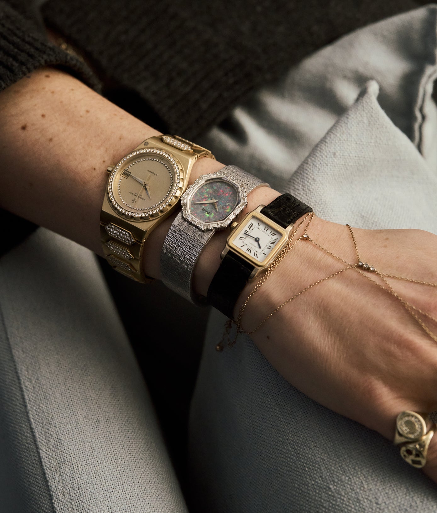 Close-up of a person's wrist wearing multiple vintage-style watches.