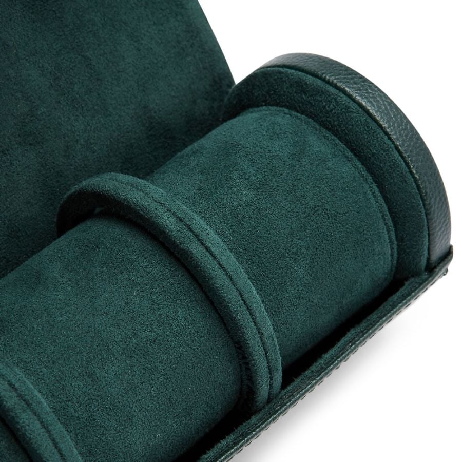 Dark green fabric watch roll with three padded compartments and leather trim, unrolled to show interior.