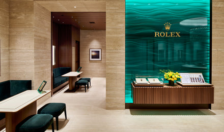 Luxury Rolex boutique interior with display cases, teal wave-pattern wall, and elegant seating.