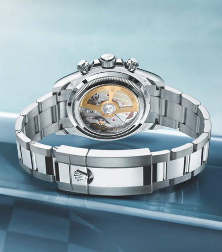 Luxury silver watch with an open back, displaying its intricate internal mechanism and bracelet clasp.