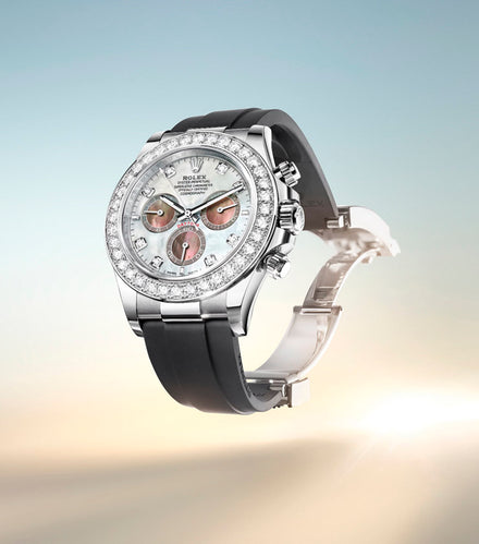 A luxury Rolex watch with a diamond bezel and black strap, displayed against a soft gradient background.