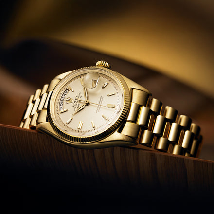 A gold luxury wristwatch with a metal band displayed on a wooden surface.