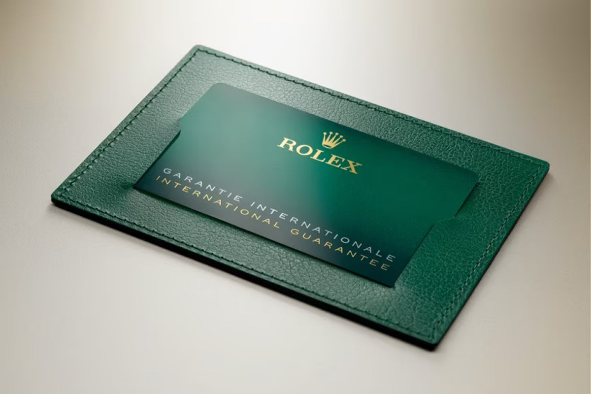 A green Rolex international guarantee card in a matching green leather holder on a beige surface.