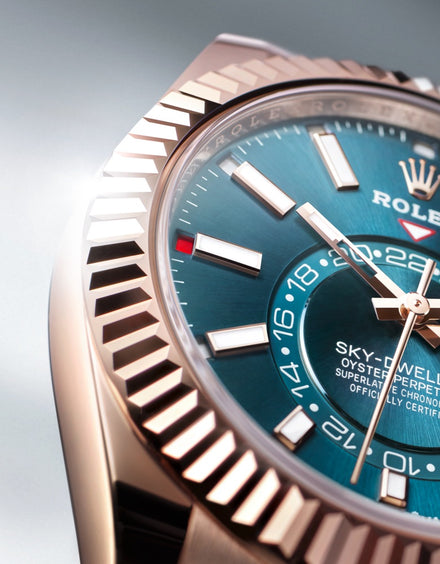 Close-up of a Rolex Sky-Dweller watch with a blue dial, gold bezel, and bold hour markers.