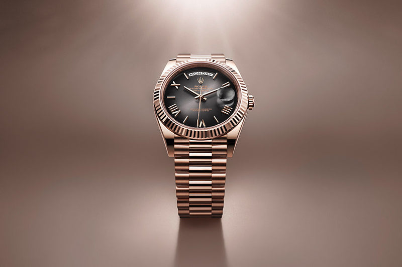 A gold luxury wristwatch with a black dial displayed on a shiny, gradient brown background.