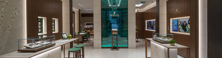 Luxurious Rolex store interior with glass display cases, green accents, and elegant lighting.