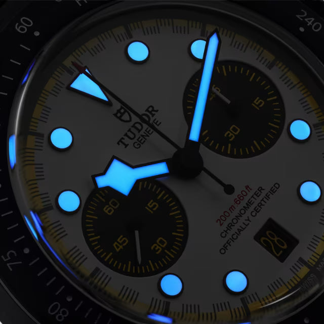 Black chronograph watch with dark dial, bright blue luminous hands and hour markers, and two subdials with yellow accents.