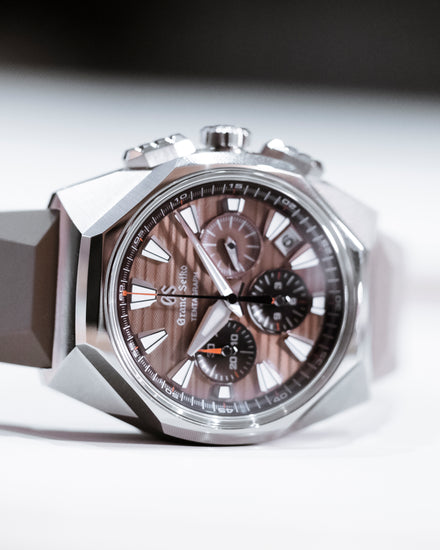 Silver Grand Seiko chronograph watch with a brown dial and rubber strap, shown at an angle.